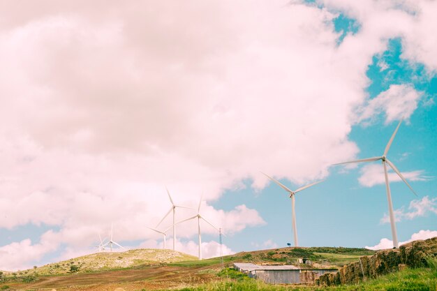 Cielo nublado sobre lo rural con molinos de viento.