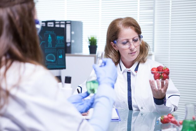 Científica caucásica mirando fresas en su laboratorio de investigación. Inspeccion de calidad.