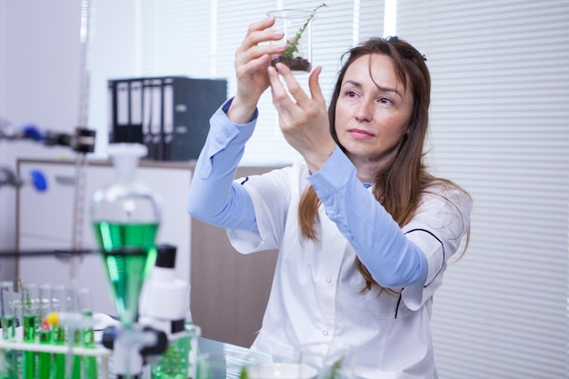 Científica sosteniendo una muestra de suelo en un laboratorio de investigación agrícola. Tubos de ensayo.