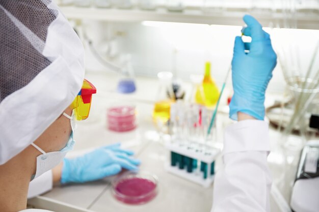 Científico atractivo joven estudiante de doctorado observando el cambio de color del indicador azul en el tubo de vidrio