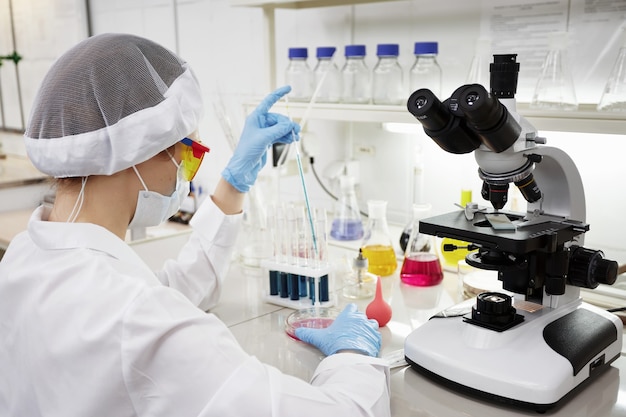 Científico atractivo joven estudiante de doctorado observando el cambio de color del indicador azul en el tubo de vidrio