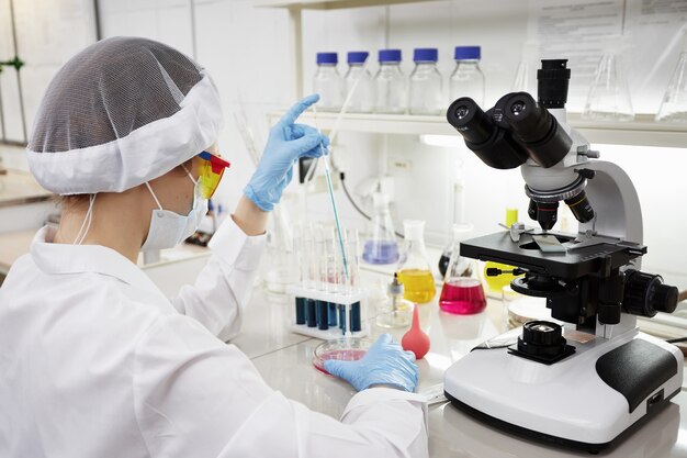 Científico atractivo joven estudiante de doctorado observando el cambio de color del indicador azul en el tubo de vidrio