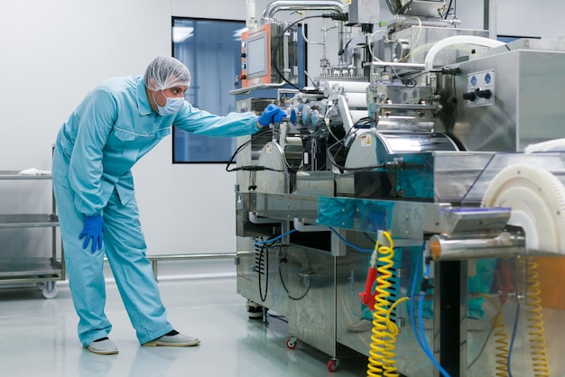 Foto gratuita científico caucásico doblado en traje de laboratorio azul tratando de arreglar la máquina de fabricación con ejes