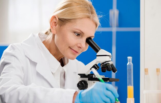 Científico femenino analizando con microscopio en el laboratorio