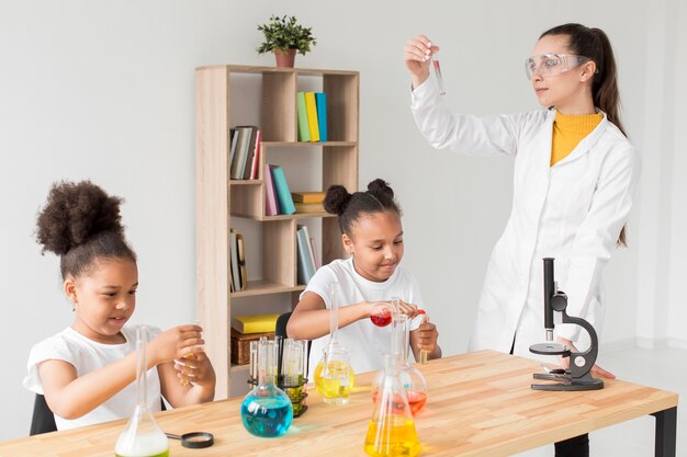 Científico femenino enseñando a niñas experimentos científicos