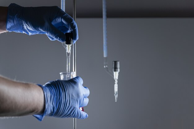 Científico en guantes médicos con tubos de ensayo y análisis de muestras químicas.