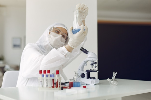 Un científico de laboratorio está examinando una solución azul en una botella.