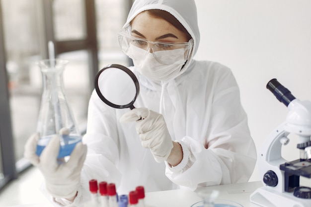 Foto gratuita un científico de laboratorio está examinando una solución azul en una botella.