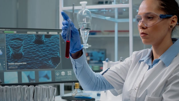 Científico de la medicina con computadora mientras sostiene el tubo de ensayo