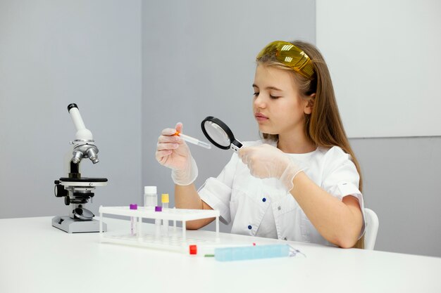 Científico de niña con gafas de seguridad y microscopio