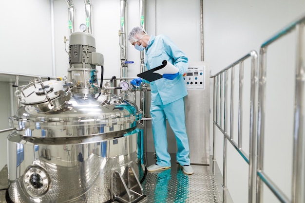 Científico en traje de laboratorio azul que trabaja con el panel de control mira la cámara