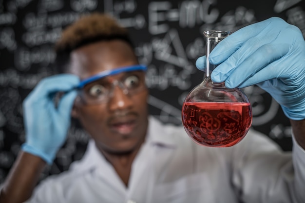 Científicos conmocionados por los químicos rojos en vidrio en el laboratorio