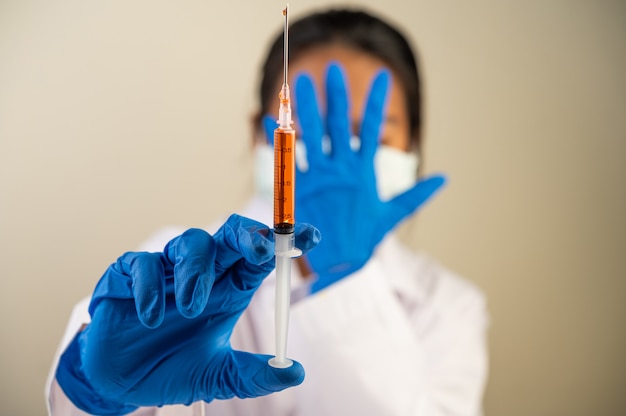 Científicos con máscaras y guantes Sosteniendo una jeringa con una vacuna para prevenir covid-19
