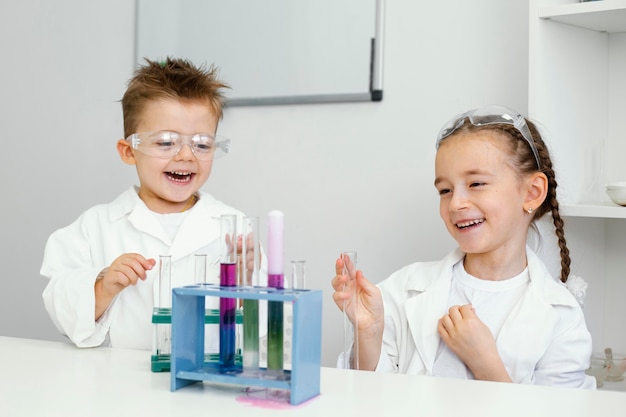 Científicos de niño y niña divirtiéndose haciendo experimentos en el laboratorio