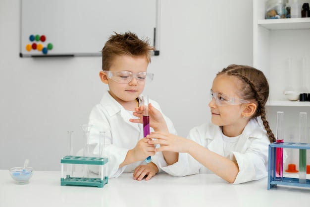 Científicos de niño y niña haciendo experimentos en el laboratorio con tubos de ensayo