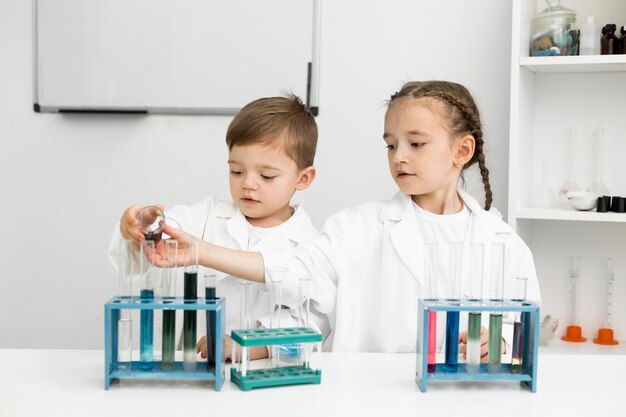 Científicos de niños pequeños lindos haciendo experimentos