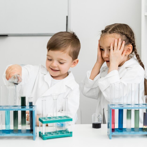 Científicos de niños pequeños lindos con tubos de ensayo haciendo experimentos