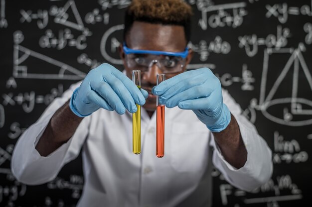Los científicos observan los químicos de color naranja y amarillo en el vidrio del laboratorio.