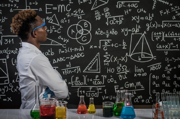 Los científicos usan anteojos y cruzan los brazos para ver la fórmula en el laboratorio