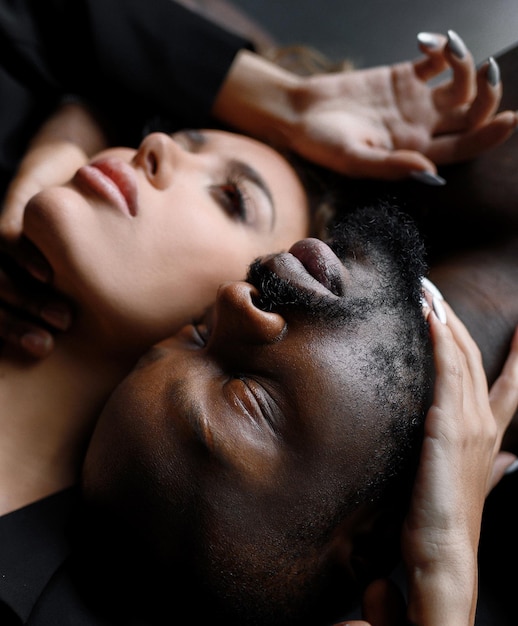 Foto gratuita cierra la cara de diversos modelos afroamericanos barbudos que yacen cerca de una hermosa chica con peinado afro y se acarician con las manos en el interior