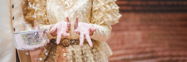 Cierra las manos de un hombre y una mujer jóvenes vestidos con hermosos trajes tailandeses que se salpican en el templo y preservan la buena cultura de los tailandeses durante el festival Songkran, Día de la Familia del Año Nuevo Tailandés en abril