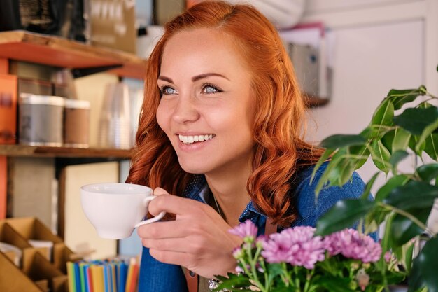 Cierra el retrato de una barista pelirroja bebe café.