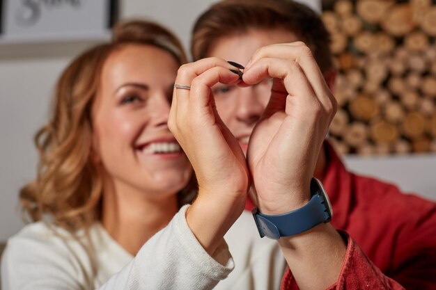 Cierra el retrato de una hermosa pareja que representa el corazón con sus propias manos, sonriendo y disfrutando de la vida