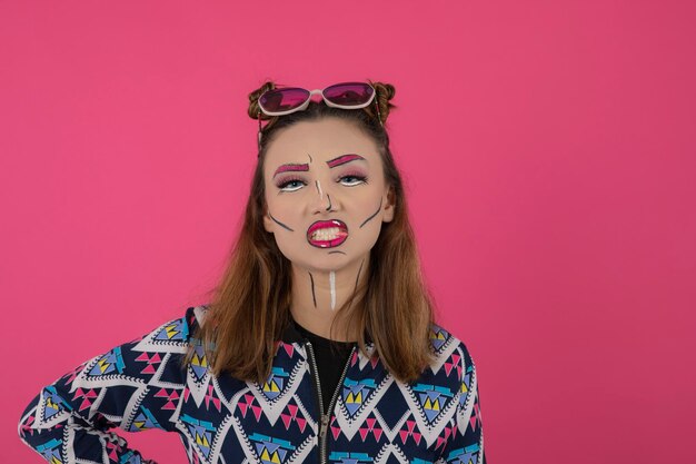 Cierra el retrato de una joven con maquillaje creativo y chicle sobre fondo rosa. foto de alta calidad