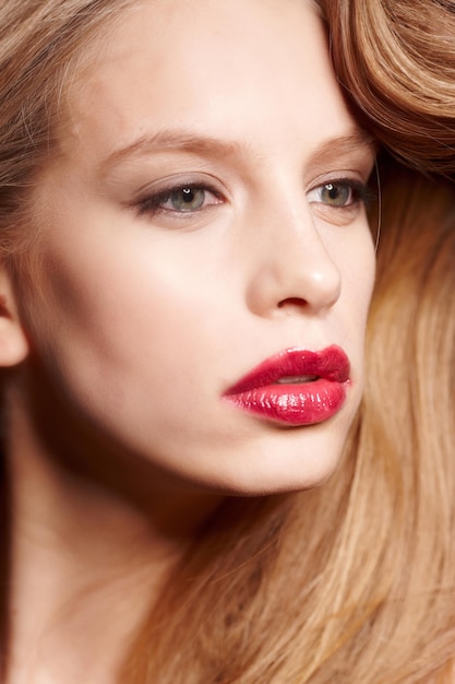 Cierra el retrato de una joven rubia con maquillaje y labios rojos.