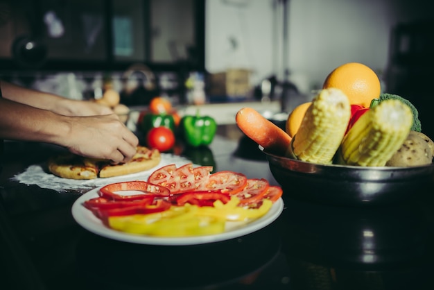 El cierre para arriba de la mano de la mujer puso el desmoche en la pizza hecha en casa.