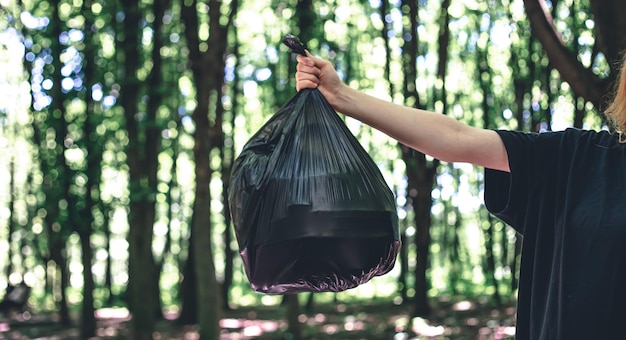 Cierre una bolsa de basura en un fondo borroso del bosque