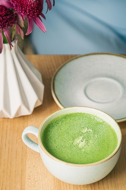 Cierre una gran taza de cerámica con una bebida de matcha verde sobre una mesa de madera