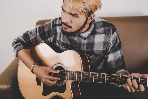 Cierre de la mano del hombre de la barba del inconformista que toca la guitarra.