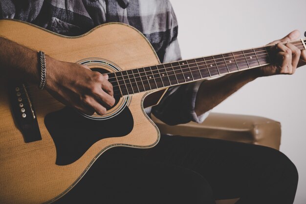 Cierre de la mano del hombre de la barba del inconformista que toca la guitarra.