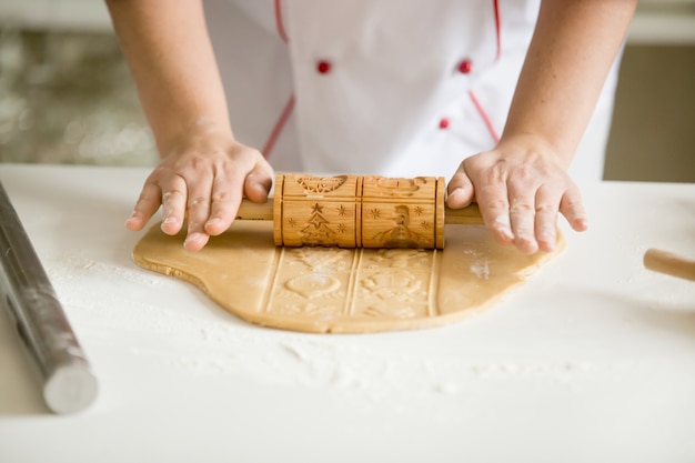 Cierre de manos rodando la masa de pan de jengibre con rolle patrón