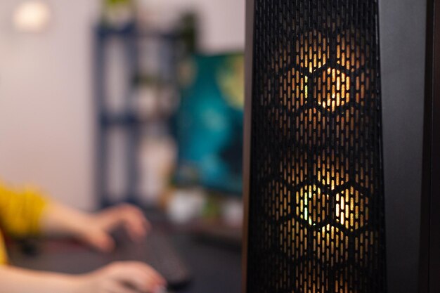 Cierre de pc para juegos con luces led rgb de pie sobre la mesa. Mujer gamer jugando videojuegos de disparos espaciales durante la competencia en línea. Estudio equipado con configuración de transmisión profesional
