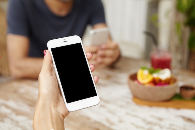 Cierre plano de la mano de mujer con teléfono móvil genérico con pantalla en blanco