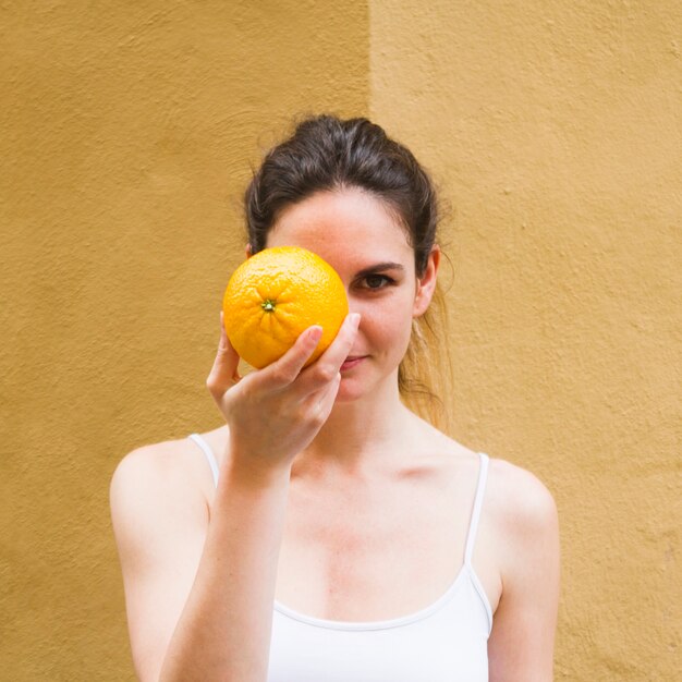 Cierre de tiro mujer que cubre la cara con naranja