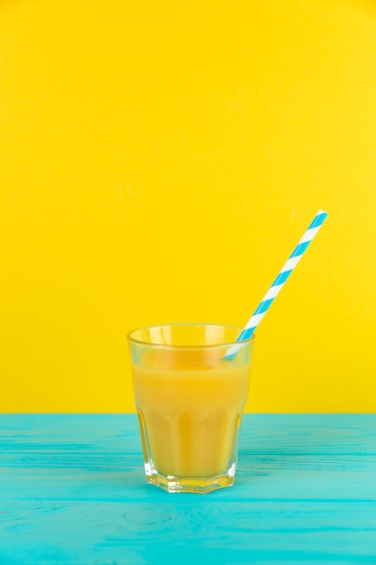 Cierre de tiro de vaso de jugo de naranja fresco con fondo amarillo