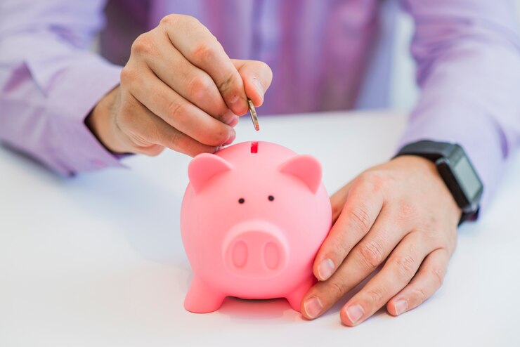 Cierre de vista de la mano de un hombre colocando una moneda en la ranura de una hucha en un concepto de ahorro e inversión