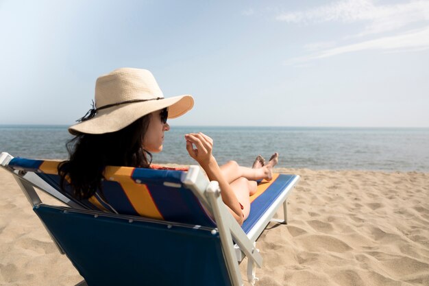 Cierre de vista trasera mujer en silla de playa mirando lejos