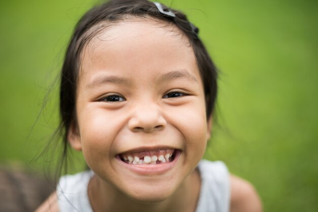 Ciérrese para arriba de la cara de la niña linda con una sonrisa que mira la cámara.