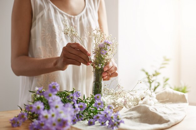 Ciérrese para arriba del florista de sexo femenino joven que hace el ramo blando en el lugar de trabajo. Copia espacio