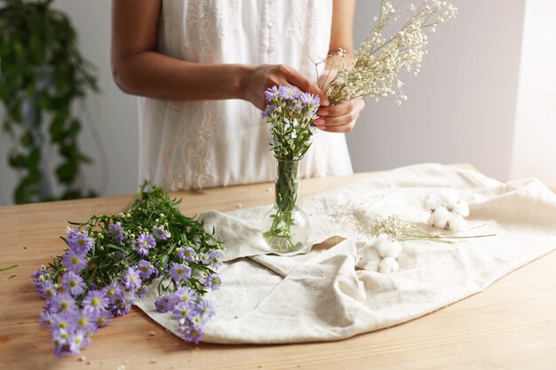 Ciérrese para arriba del florista de sexo femenino joven que trabaja con el ramo de flores en el lugar de trabajo.