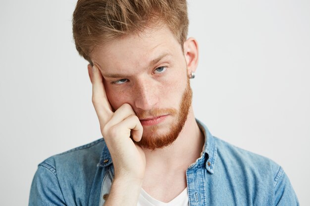 Ciérrese para arriba del hombre joven cansado aburrido que sostiene el dedo en el templo.