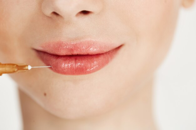 Ciérrese para arriba de la inyección médica del botox en labios. Tratamiento facial.