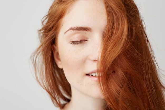 Ciérrese para arriba de muchacha hermosa tierna joven con el pelo rojo que sonríe con los ojos cerrados.