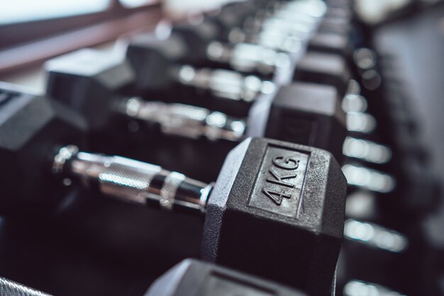 Ciérrese para arriba de muchas pesas de gimnasia del metal en el estante en gimnasio de deporte.