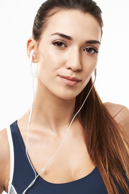 Ciérrese para arriba de mujer deportiva en los auriculares que presentan en blanco.