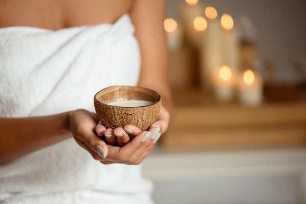 Ciérrese para arriba de la mujer que sostiene el coco en salón del balneario.